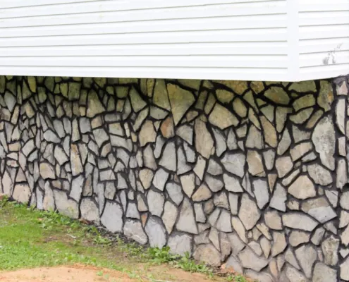 Stone foundation facing below white siding