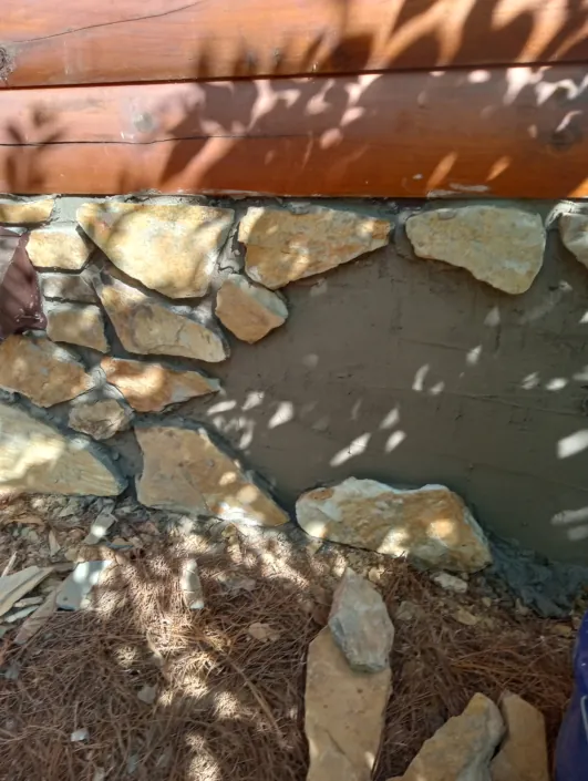 Fieldstone veneer being set on a log home foundation