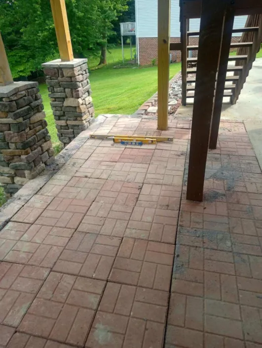 New brick paver patio between stacked stone columns