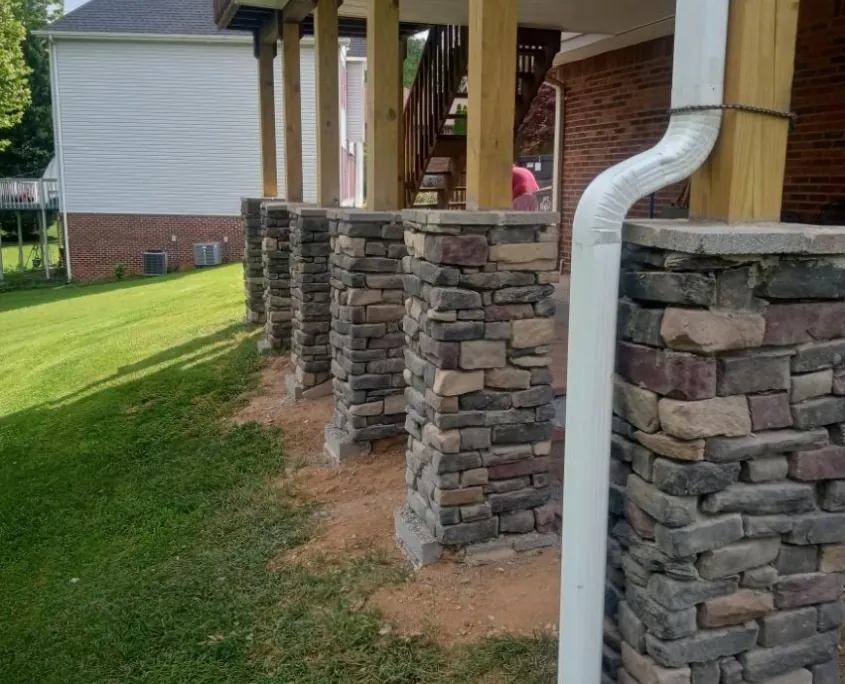 Stone masonry columns supporting a raised porch by Hudson Stoneworks