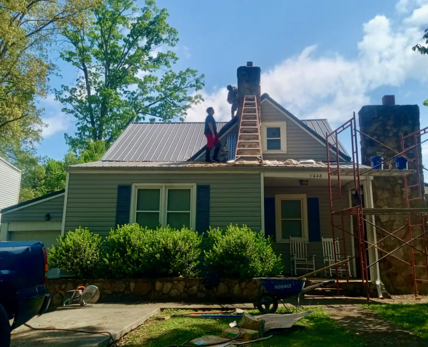 Masonry crew working on stone chimneys with ladders and scaffolding