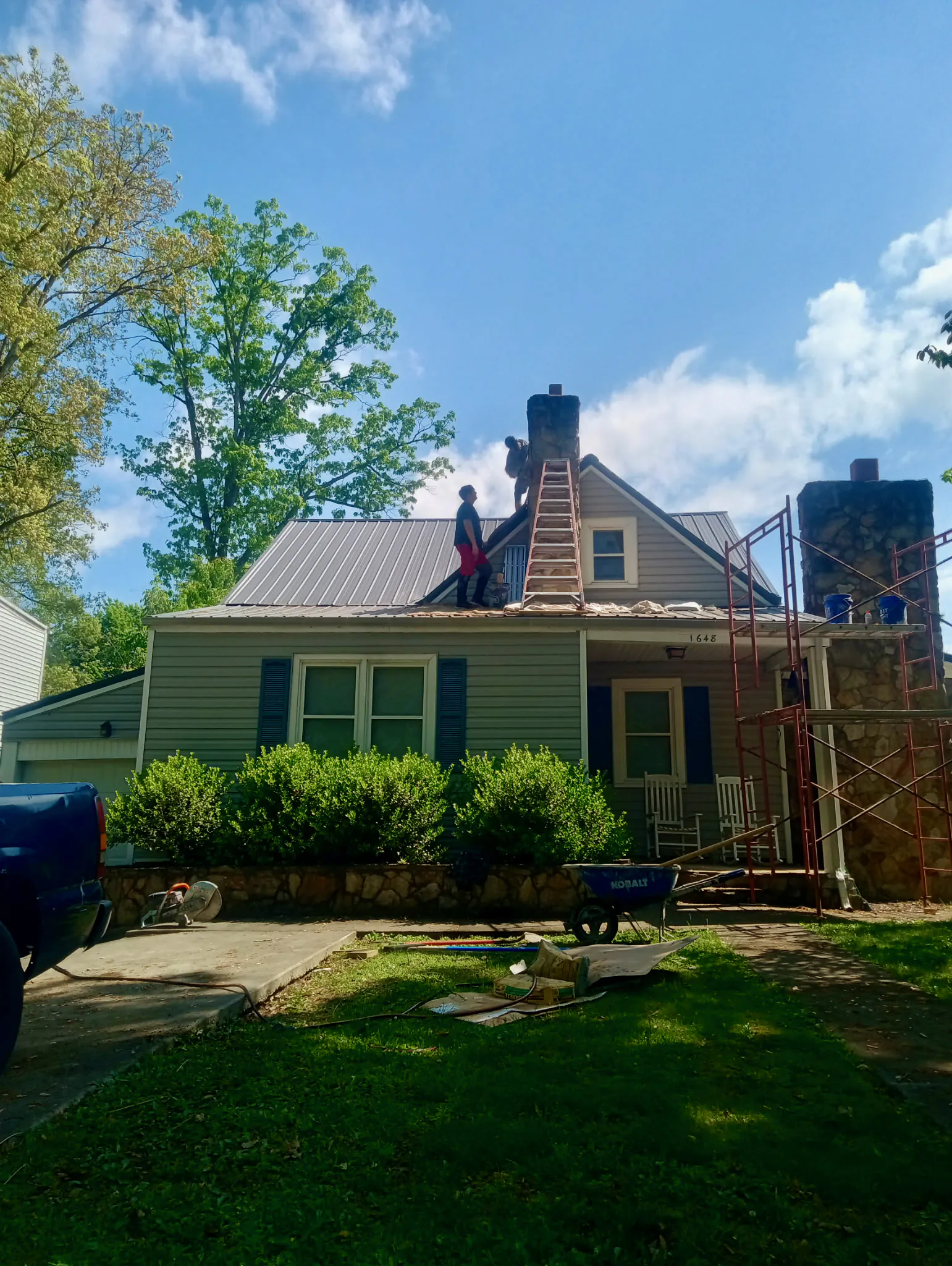 Masonry crew working on stone chimneys with ladders and scaffolding