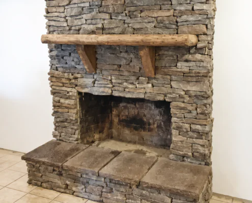 Stone fireplace with timber mantel and raised hearth